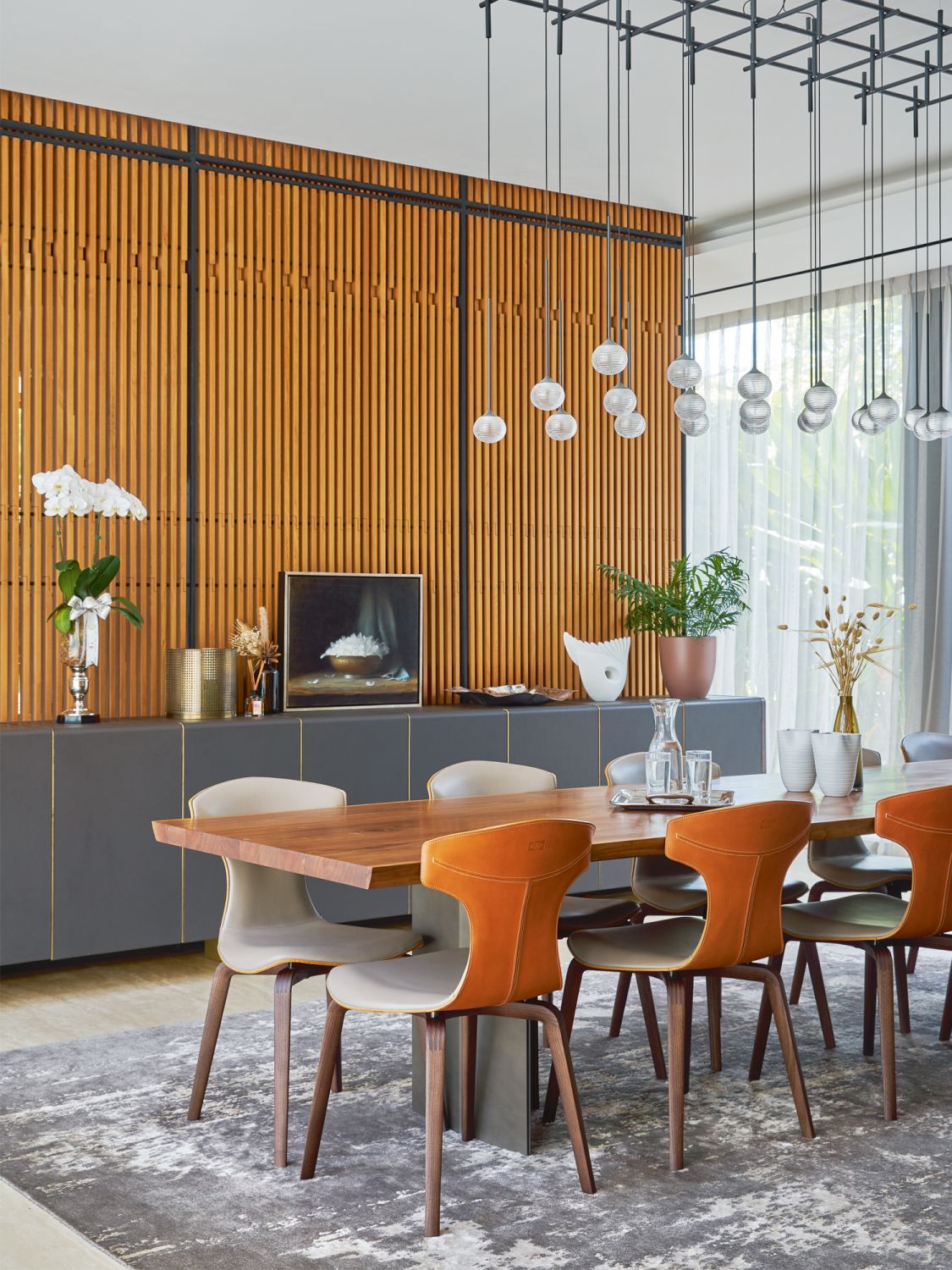 The leather backs of the Poltrona Frau Montera dining chairs by Roberto Lazzeroni echo the warm hue of the wooden wall panelling