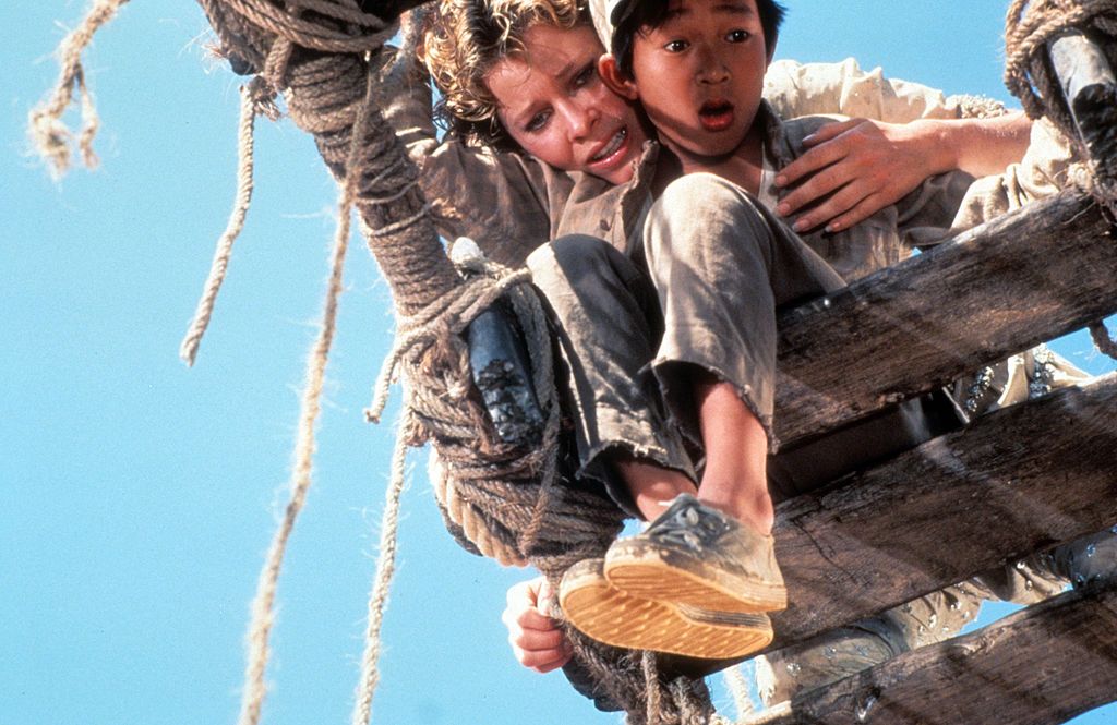 Kate Capshaw holds onto Jonathan Ke Quan over a broken bridge in a scene from the film 'Indiana Jones And The Temple Of Doom', 1984. (Photo by Paramount/Getty Images)