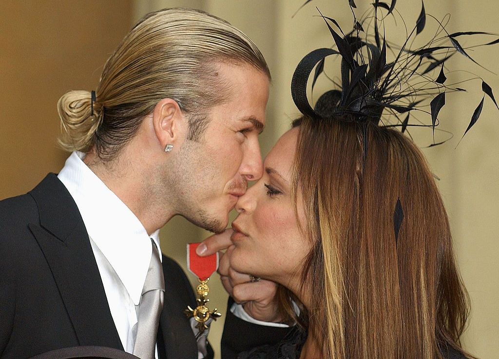 LONDON - NOVEMBER 27: NO UK SALES FOR 28 DAYS England football captain David Beckham kisses his wife Victoria, as he shows off the OBE (Officer of the Order of the British Empire) he received from Britain's Queen Elizabeth II at Buckingham Palace on November 27, 2003 in London. (Photo by ROTA/Getty Images)