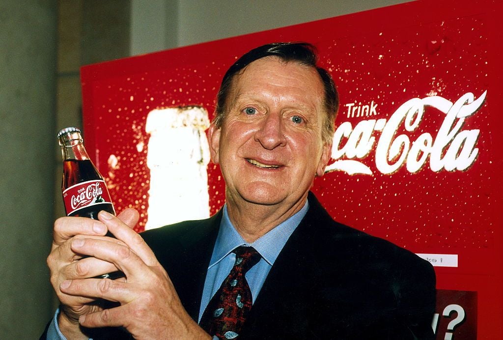 (GERMANY OUT) 1943-Wirtschaftsmanager; USAPräsident der Coca-Cola Co.- Porträt vor einer Werbetafel mit dem Coca-Cola-Schriftzug; hält eine Cola-Flasche in der Hand- ohne Jahr (Photo by Henry Herrmann/ullstein bild via Getty Images)