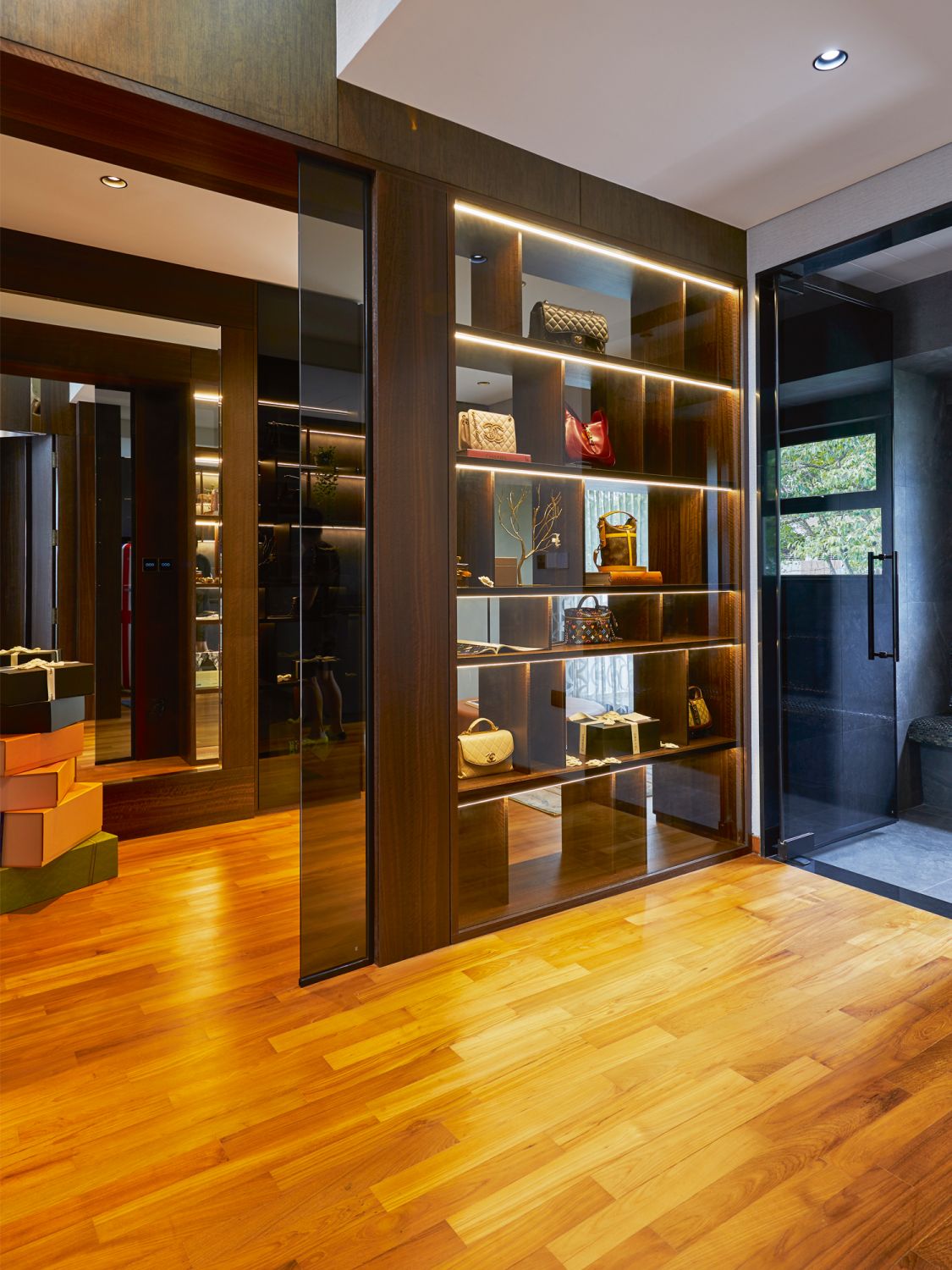 The wife’s wardrobe area in the attic is designed with backlit shelves that showcase her collection of bags and other accessories