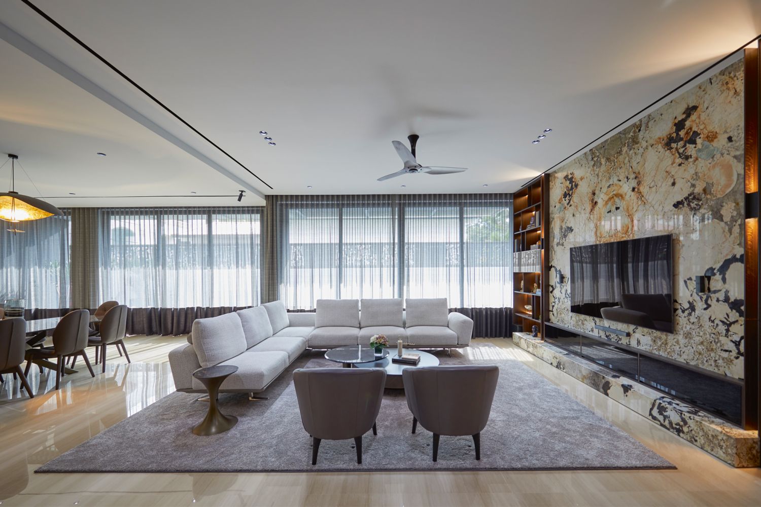 The open-plan living area is furnished with the Bellaire sofa and Boulevard armchairs from King, Cattelan Italia Arena Bond coffee table from Royal Interiors and Tonin Casa Andorra side table from Marquis QSquare, with the Catellani & Smith Lederam Manta suspension light in the dining area echoing the delicate gold detailing of the Patagonia quartzite feature wall
