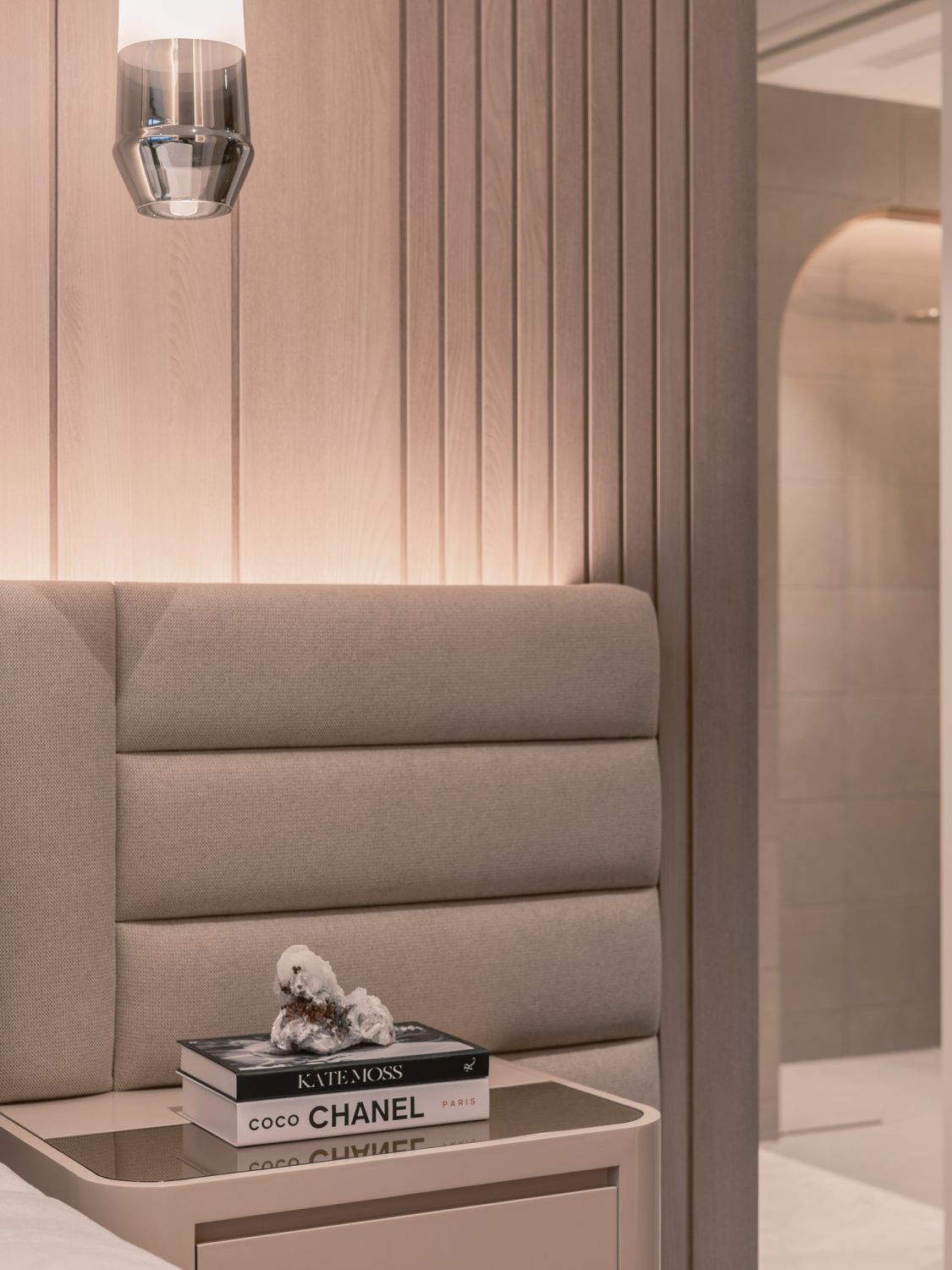 The custom headboard features ribbed details that stand in contrast to the vertical wooden slats on the feature wall