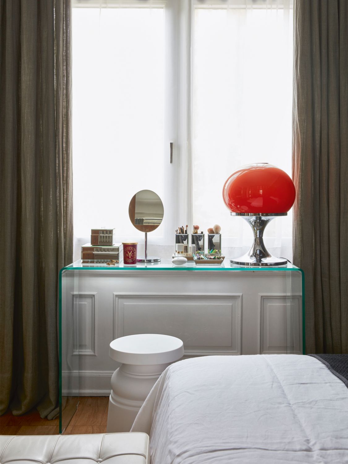 The glass console is from Zara Home, while the orange lamp and stool are vintage finds from Los Angeles