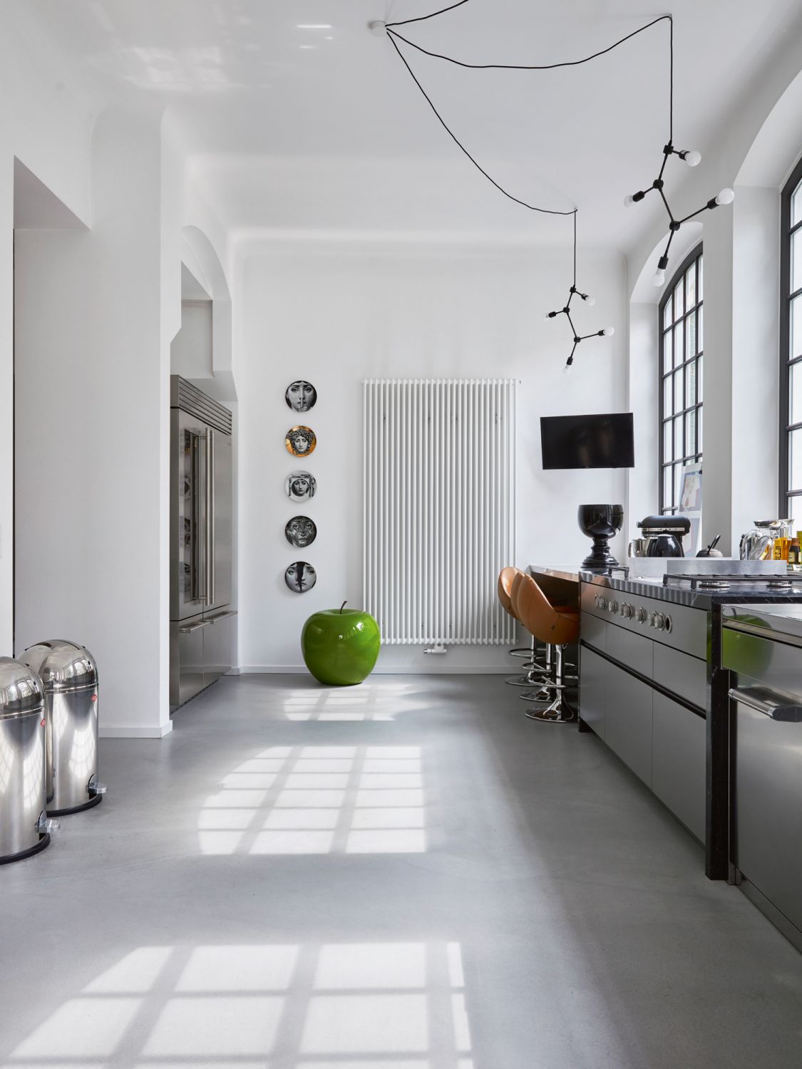 The wall-hung plates from Fornasetti, along with a large apple-shaped sculpture from 1stdibs.com add a sense of whimsy to the kitchen