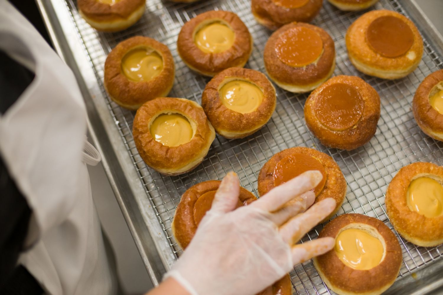 Adding finishing touches to Kora’s famed leche flan doughnuts
