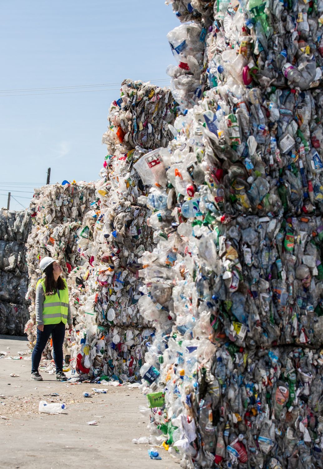 Sorted waste bundles tower above Miranda Wang at Californiaâs GreenWaste Recovery facility.
