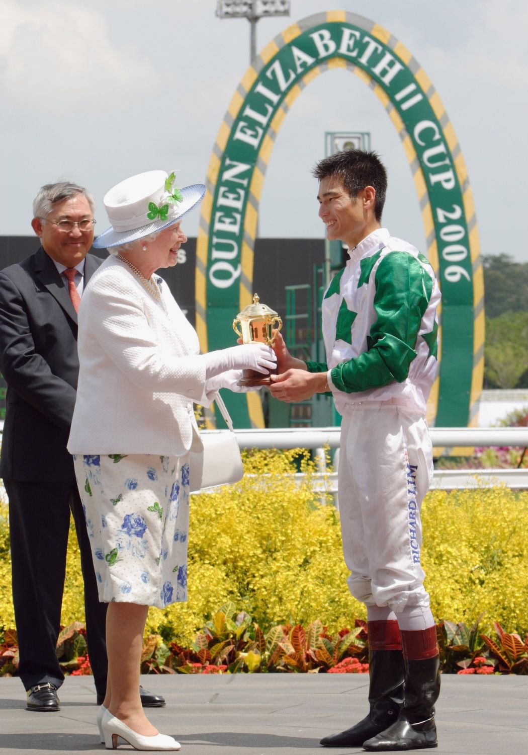 Queen Elizabeth II presents a trophy to jockey Richard Lim after he rode "King And King" to victory in the Queen Elizabeth II Cup at the Singapore Turf Club on 18 March, 2006 in Singapore. The British monarch visited Singapore's horse racing tracks to watch the Queen Elizabeth II Cup race. (Photo: Getty Images)