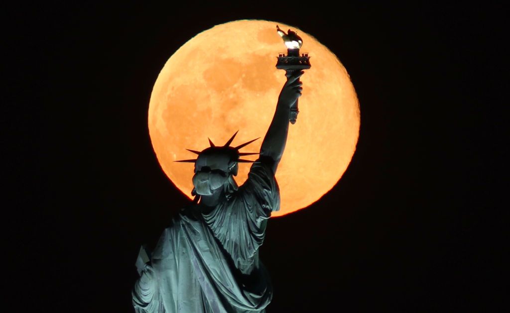 JERSEY CITY, NJ - MAY 7: The Super Flower Moon rises behind the Statue of Liberty in New York City on May 7, 2020 as seen from Jersey City, New Jersey. (Photo by Gary Hershorn/Getty Images)