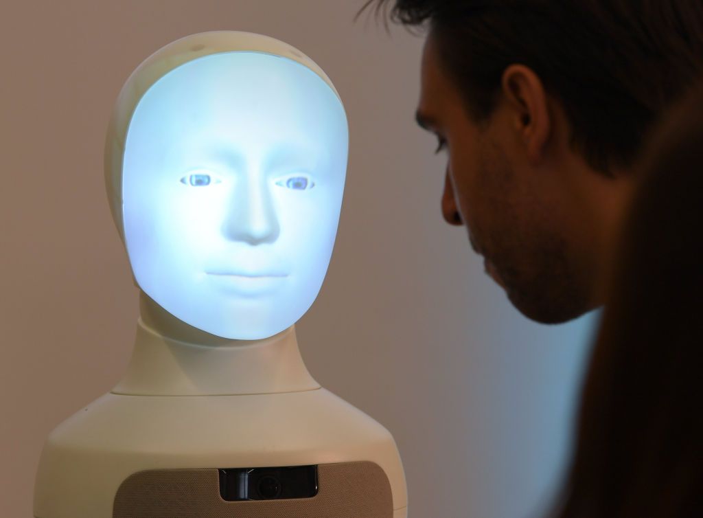 31 August 2020, Hessen, Darmstadt: Patrick Schanowski, research assistant, communicates during a press conference at the TU Darmstadt with robot "Alfie", a Moral Choice Machine. A Center for Artificial Intelligence (AI) is to be established in Darmstadt. The state of Hesse is providing 38 million euros for this over the next five years. The center will be involved in basic research, but also in the application of AI. Photo: Arne Dedert/dpa (Photo by Arne Dedert/picture alliance via Getty Images)
