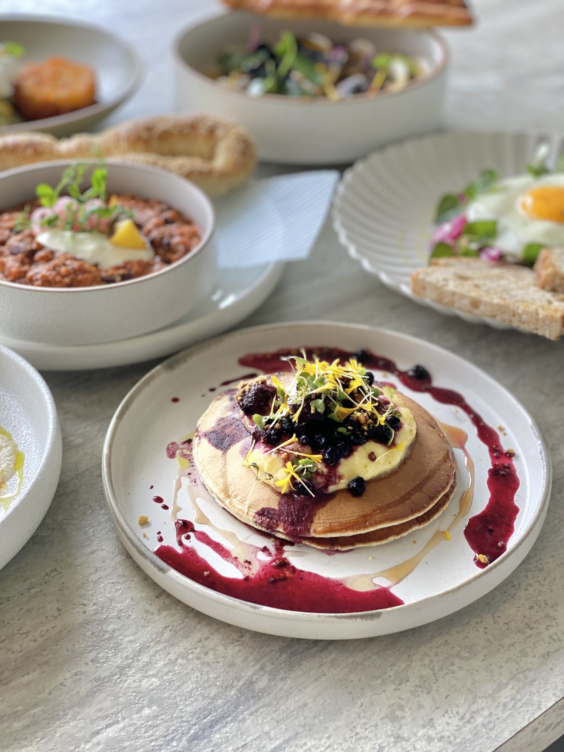 Tucker's hotcakes with orange curd, berries compote, crushed pistachio and maple syrup