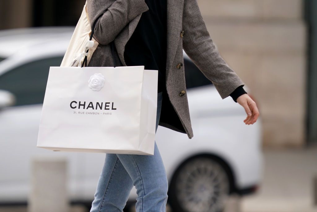 PARIS, FRANCE - MAY 11: A passerby wears a gray jacket and holds a white Chanel shopping bag, in the streets of Paris, on May 11, 2020 in Paris, France. (Photo by Edward Berthelot/Getty Images)