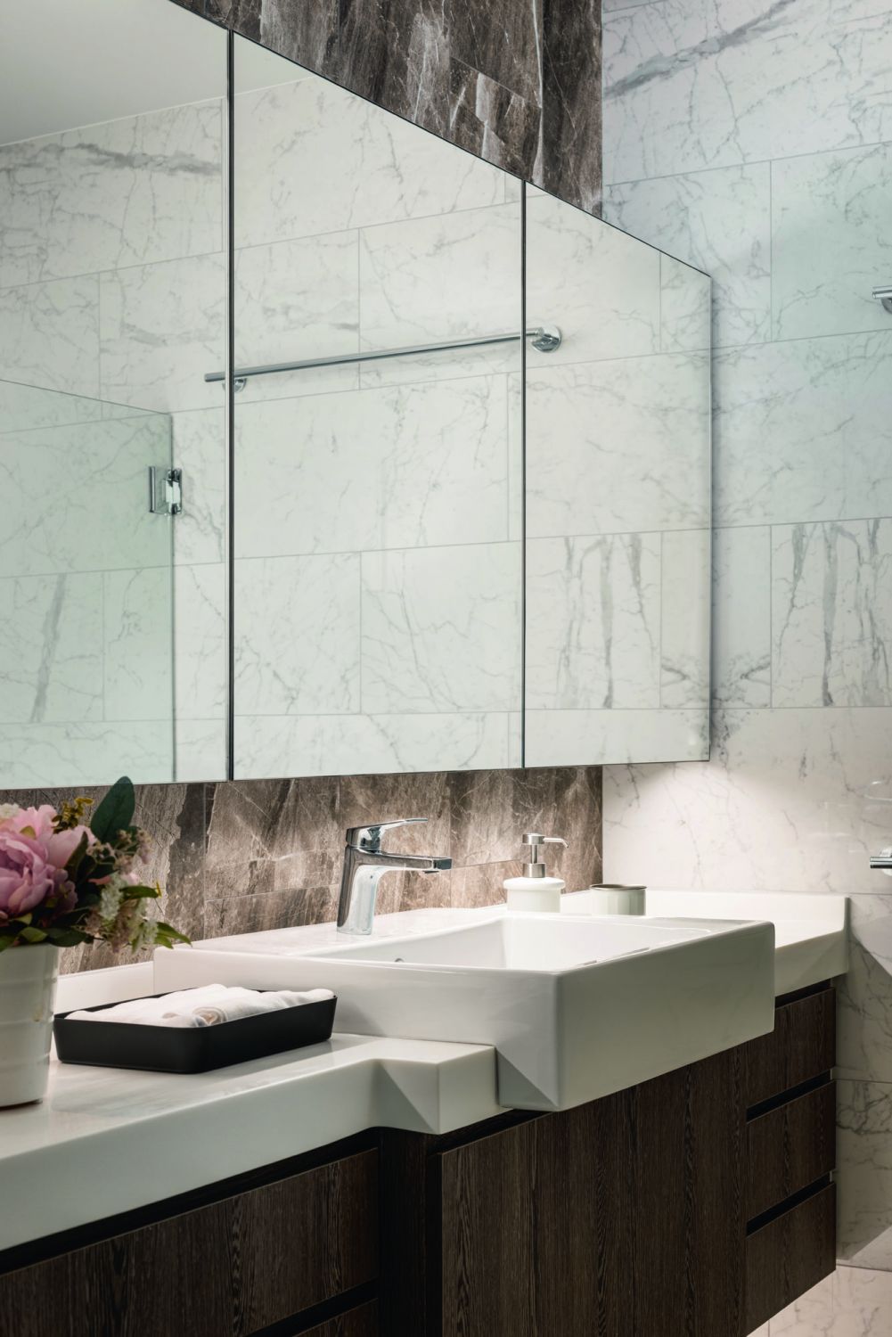 The use of light porcelain tiles with a marble-like pattern brightens the look of this bathroom