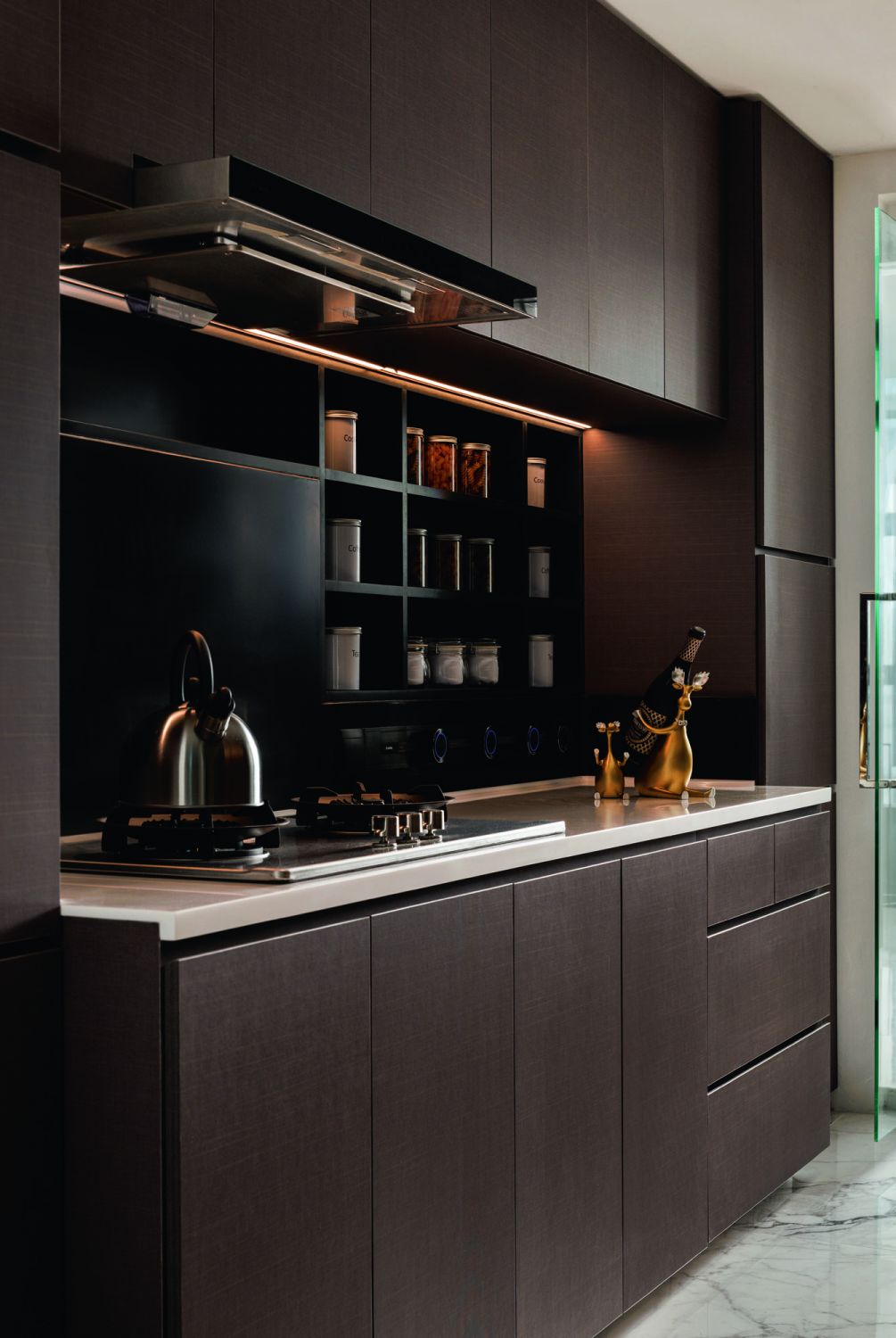 The kitchen features white solid surface countertops, with a concealed LED lighting strip overhead for added illumination