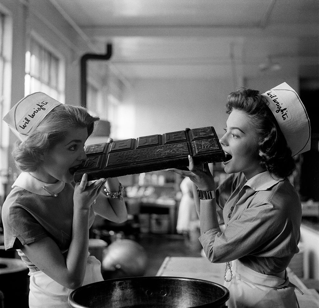 LOS ANGELES,CA - JUNE 13,1955: Actress Natalie Wood and actress Leigh Snowden takes a bite of a chocolate bar as they pose working at a Wil Wright's ice cream parlor in Los Angeles,CA.  (Photo by Earl Leaf/Michael Ochs Archives/Getty Images)