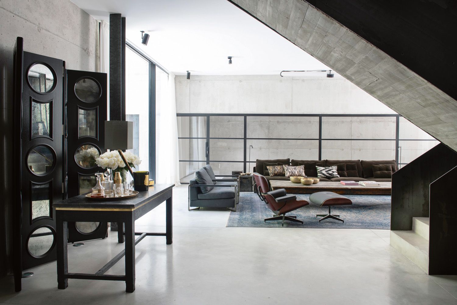 Custom furnishings and vintage pieces in dark wood and matte-black finishes feature throughout the interior to complement the ironwork and minimalist scheme of the abode