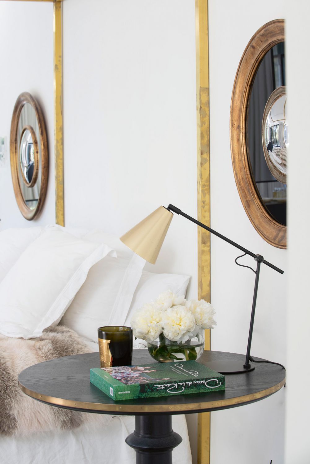 The patinated finish of the four-poster bed and bronze mirrors adds character to the interior