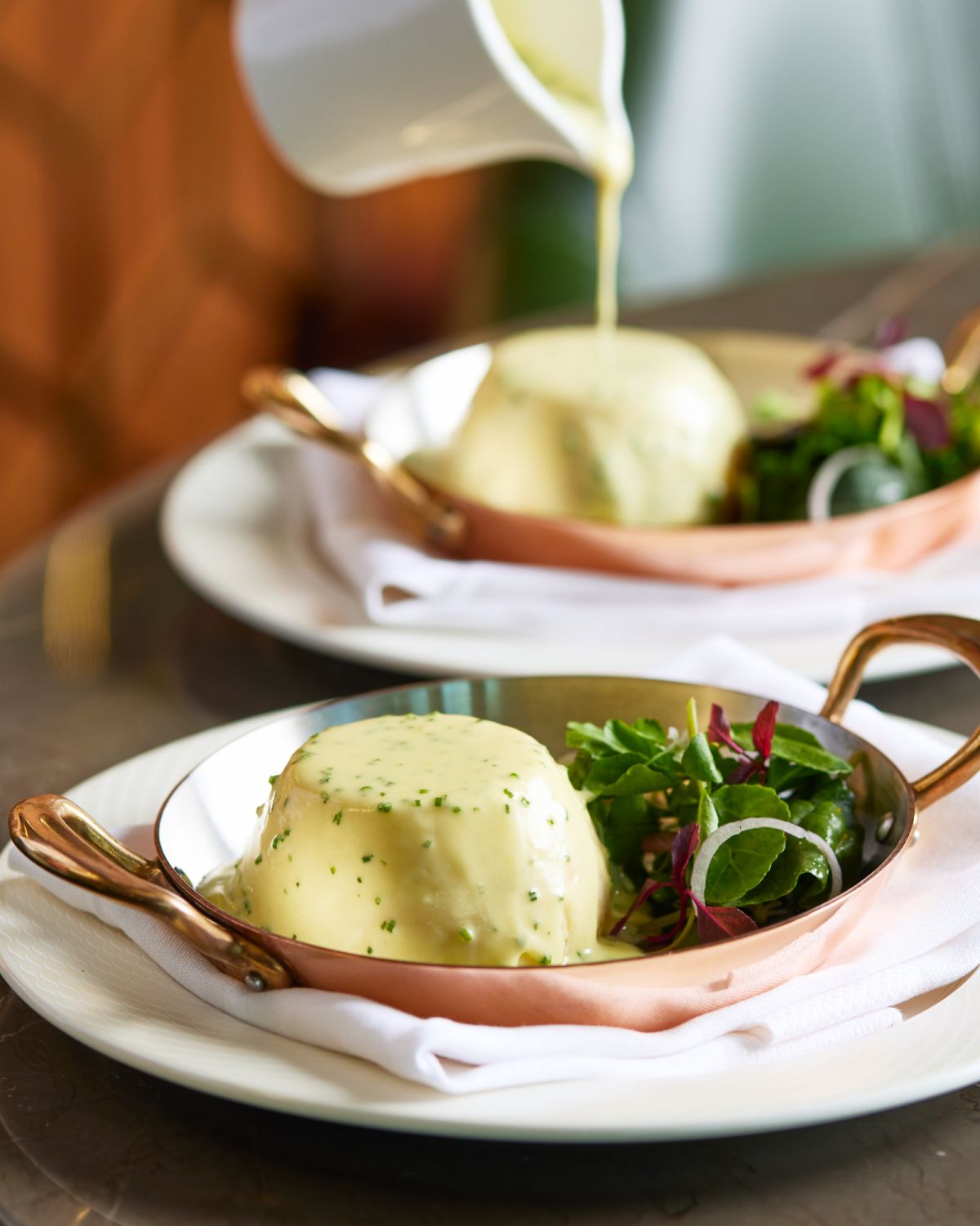 The Arnold Bennett Twice-baked Soufflé with smoked haddock is served with a rich and creamy aged cheddar sauce and a fine herb salad.