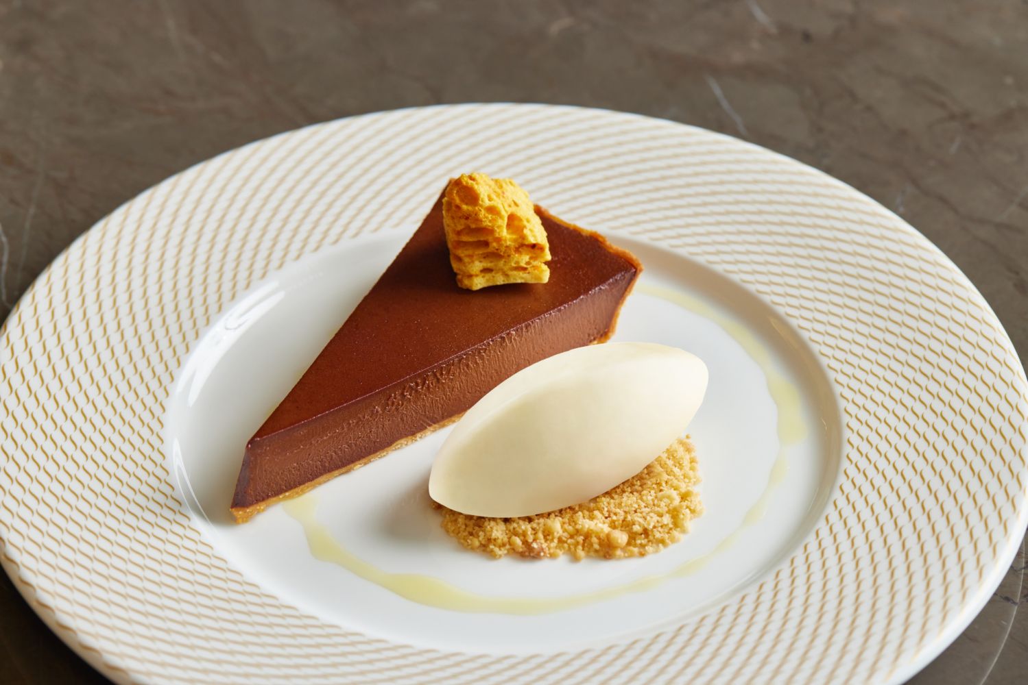 The 64% Manjari Chocolate Tart is served with a honeycomb and buttermilk sorbet, making it a perfect ending to any meal.