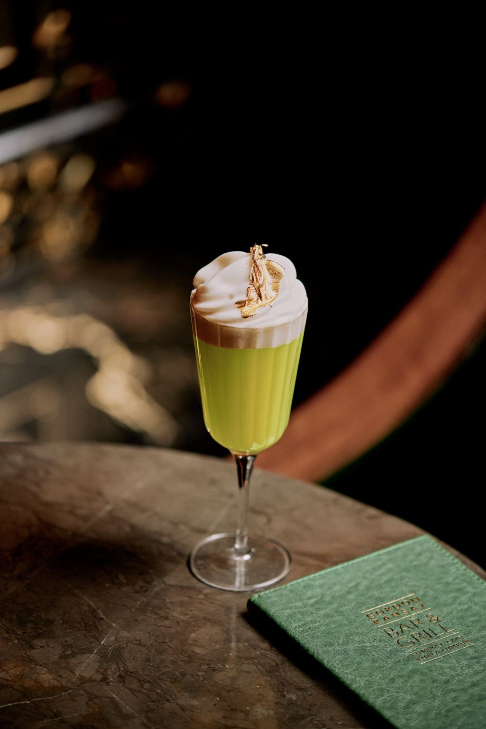 One of the restaurant's signature cocktails, the Chelsea Royal Garden, made with lemon bitters, green apple juice, St. Germain, and prosecco, topped with apple foam and a gold leaf.