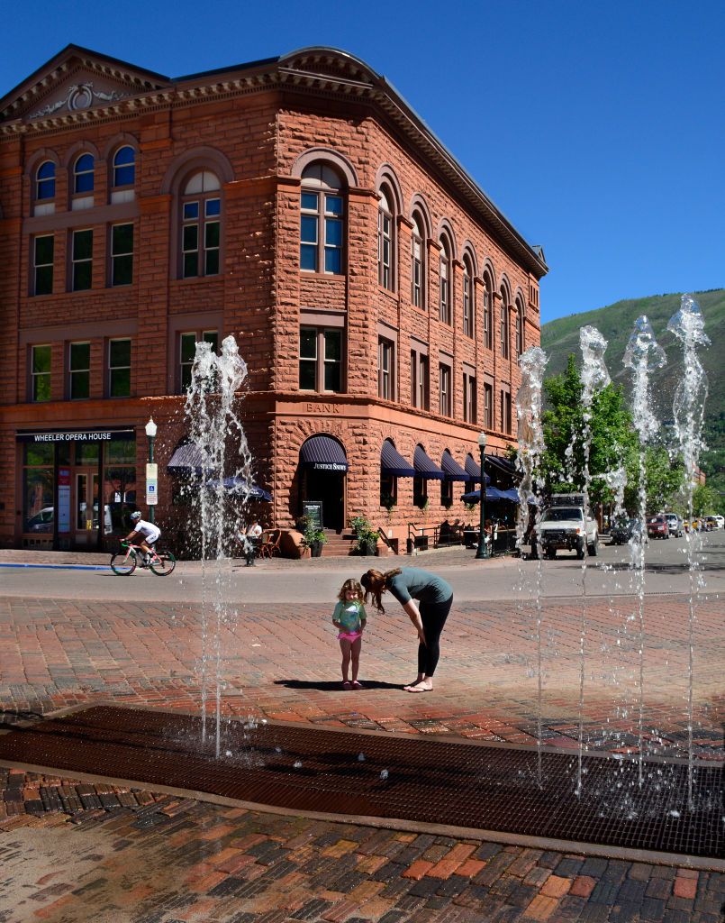 ASPEN, CO - JUNE 10, 2017: A woman encourages her reluctant young daughter to enjoy the Aspen Dancing Fountain in Aspen, Colorado. Built in 1979, the fountain is a popular summer playground for children. (Photo by Robert Alexander/Getty Images)
