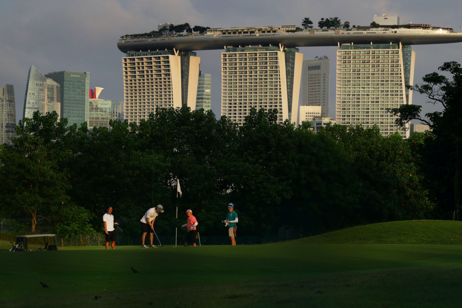 People playing golf are pictured against the Marina Bay Sands and the Central Business District on June 29, 2022 in Singapore. (Photo by Suhaimi Abdullah/NurPhoto via Getty Images)