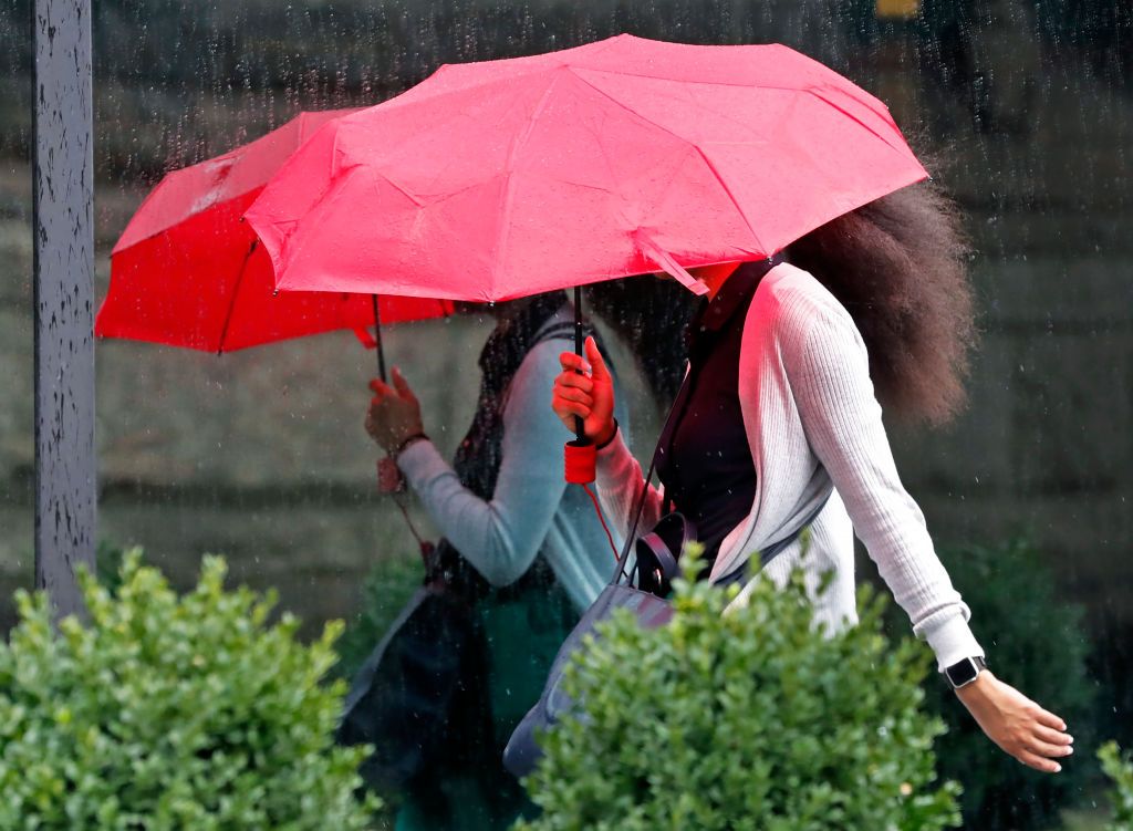 Boston, MA - July 18: A pedestrian is reflected in a window of the John Hancock Building as she uses an umbrella to protect herself from the rain. (Photo by Jim Davis/The Boston Globe via Getty Images)