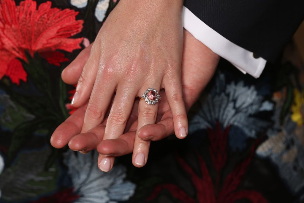 LONDON, ENGLAND -JANUARY 22: Princess Eugenie wears a ring containing a padparadscha sapphire surrounded by diamonds as she poses with Jack Brooksbank in the Picture Gallery at Buckingham Palace after they announced their engagement. Princess Eugenie wears a dress by Erdem, shoes by Jimmy Choo and a ring containing a padparadscha sapphire surrounded by diamonds on January 22, 2018 in London, England.. They are to marry at St George's Chapel in Windsor Castle in the autumn this year. (Photo by Jonathan Bra