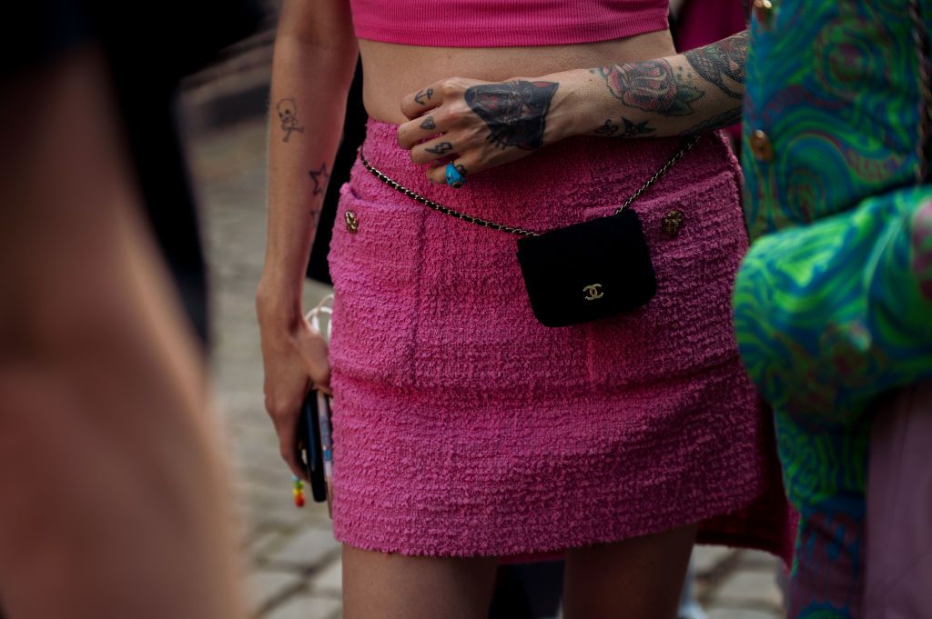 COPENHAGEN, DENMARK - AUGUST 09: Marianne Theodorsen wearing pink miniskirt and pink top with black mini Chanel bag on her waist posing outside A. Roege Hove show during Copenhagen Fashion Week Spring/Summer 2023on August 09, 2022 in Copenhagen, Denmark. (Photo by Raimonda Kulikauskiene/Getty Images)