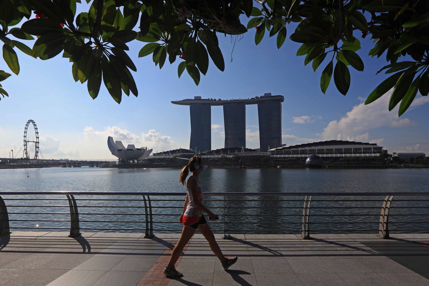 SINGAPORE - MAY 26: A woman wearing protective mask walks along the waterfront with the Singapore Flyer, ArtScience museum and Marina Bay Sands pictured in the background on May 26, 2020 in Singapore. Singapore is set to ease the partial lockdown measures against the coronavirus (COVID-19) pandemic after 1 June in three phases to resume activities safely after it sees a decline in the new infection cases in the community. Singapore's gross domestic product (GDP) is expected to shrink as much as 7 percent t