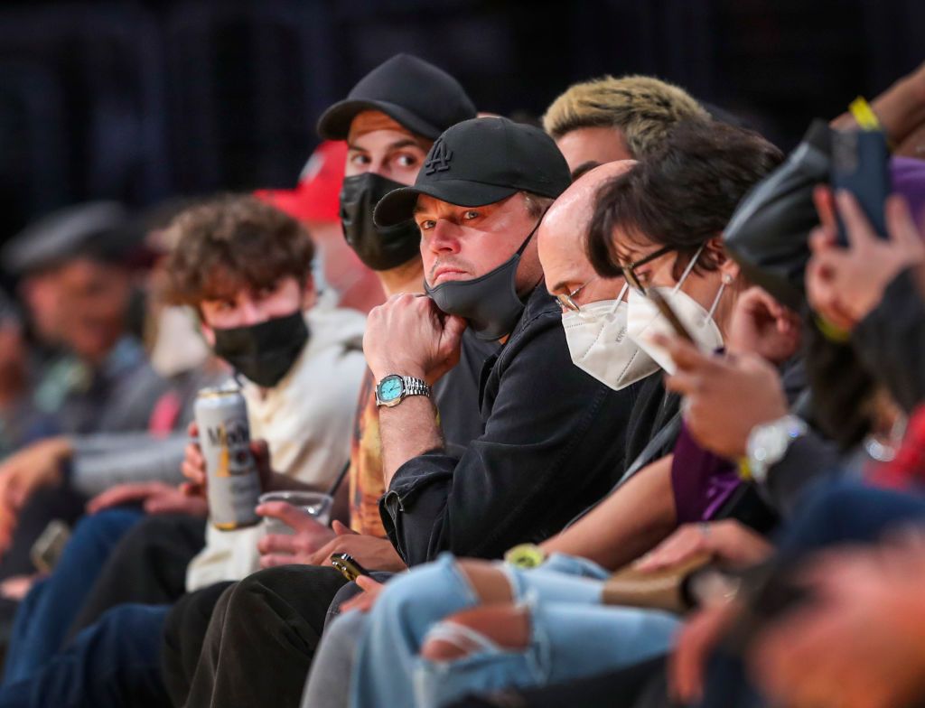 Los Angeles, CA - February 02: Actor Leonardo DiCaprio, center in black hat with mask partly down, sits next to film producer Jeffrey Katzenberg, right of him with white mask, as they attend the Los Angeles Lakers-Portland Trail Blazers basketball game at Crypto.com Arena on Wednesday, Feb. 2, 2022 in Los Angeles, CA. (Allen J. Schaben / Los Angeles Times via Getty Images)