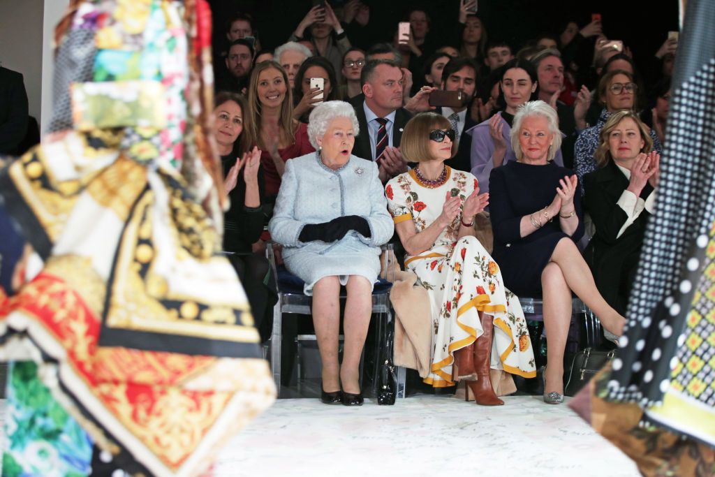 LONDON, ENGLAND - FEBRUARY 20: Queen Elizabeth II sits with Anna Wintour, Caroline Rush (L), chief executive of the British Fashion Council (BFC) and royal dressmaker Angela Kelly (R) as they view Richard Quinn's runway show before presenting him with the inaugural Queen Elizabeth II Award for British Design as she visits London Fashion Week's BFC Show Space on February 20, 2018 in London, United Kingdom. (Photo by Yui Mok - Pool/Getty Images)
