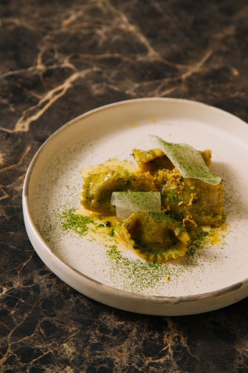 The miso beef agnolotti is topped with parsley powder and sliced daikon