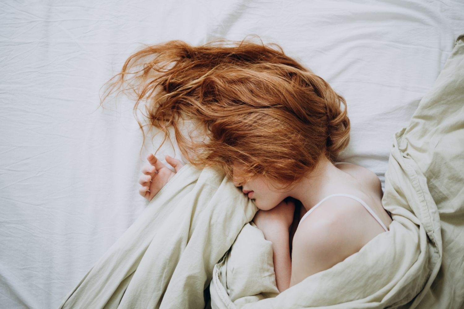 Red-haired little girl wakes up in the morning in her crib.