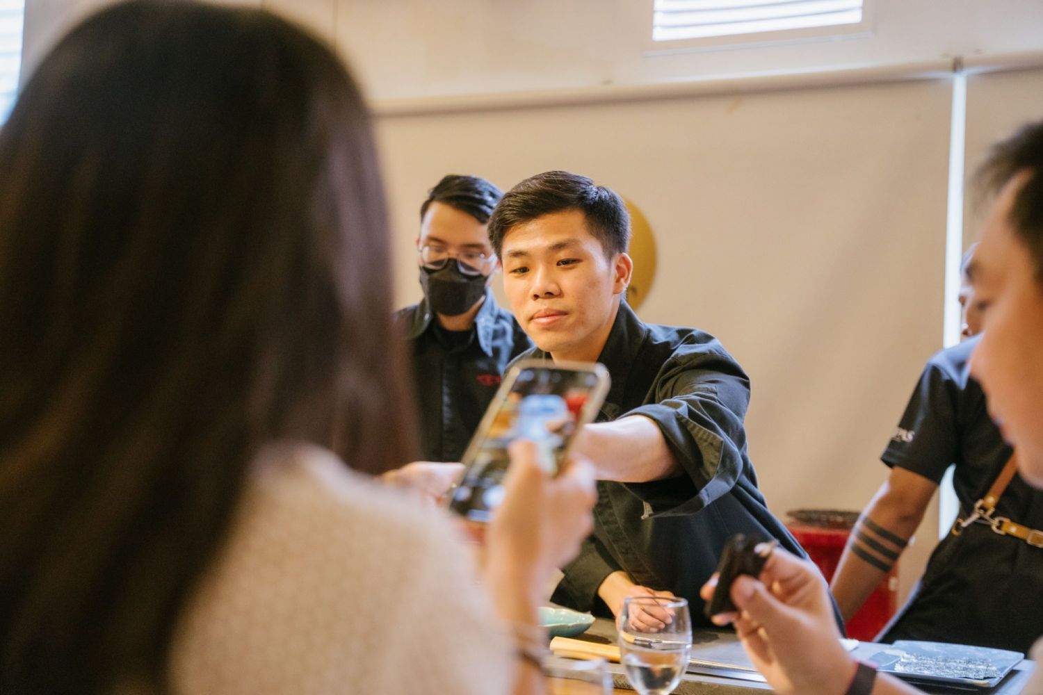 Nicholas Yap passing a diner her tossaki (tuna collar) roll