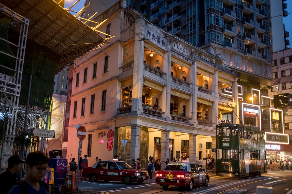HONG KONG, CHINA - JULY 12: A tram passes in front of the heritage building "The Pawn" on July 12, 2019 in Hong Kong, China. The Pawn is a four story 19th century heritage building which now houses a restaurant and bar and is favorite tourist attracti on of the Wan Chai district. Hong Kong is approaching a political crossroads after two months of widespread protests over a proposed extradition bill, which raise more fundamental questions about its relationship with mainland China. Since 1997, when it was ha