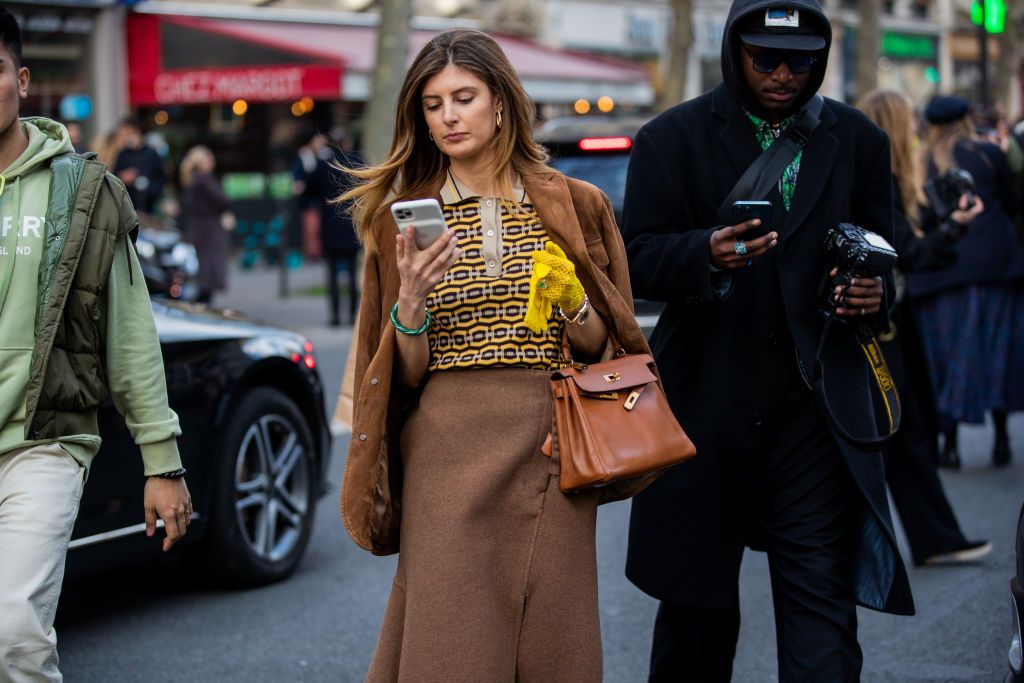 PARIS, FRANCE - MARCH 05: A guest is seen wearing brown jacket, skirt, bag Hermes, yellow gloves outside Hermes during Paris Fashion Week - Womenswear F/W 2022-2023 on March 05, 2022 in Paris, France. (Photo by Christian Vierig/Getty Images)