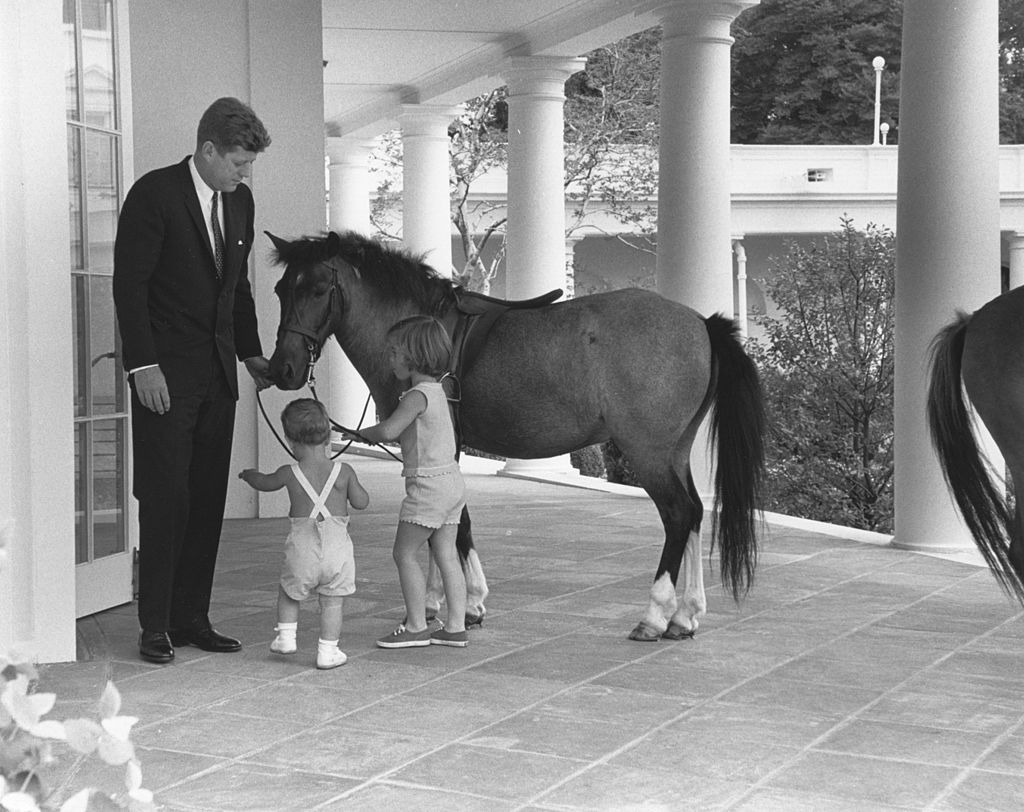 Outside the White House's Oval Office, American President John F. Kennedy (1917 - 1963) and his children, John (1960 - 1999) and Caroline, play with pony Macaroni, Washington DC, June 22, 1962. (Photo by Photoquest/Getty Images)