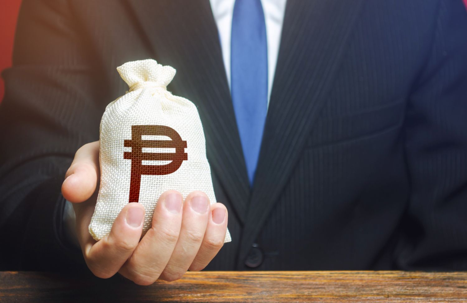 A businessman holds in his hand a philippine peso money bag. nvestments, financing. Stimulating economic recovery. Providing business with preferential loans and support during the economic crisis. I