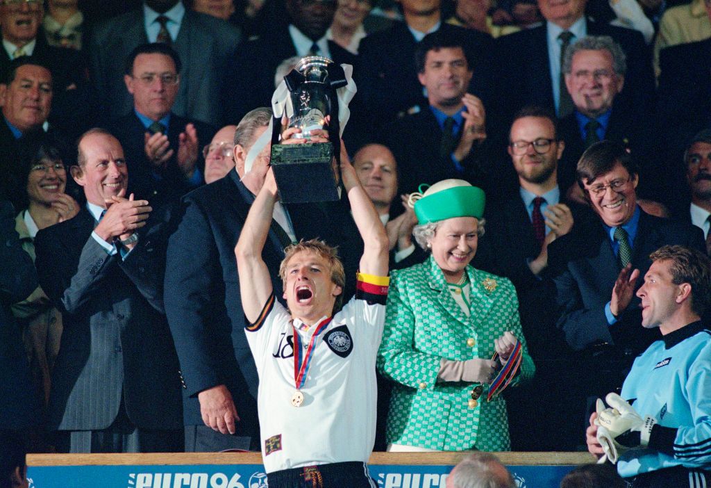 LONDON, ENGLAND - JUNE 30: Germany captain Jurgen Klinsmann lifts the trophy as Her Majesty Queen Elizabeth II smiles and goalkeeper Andreas Kopke (r) looks on after the 1996 UEFA European Championships Final against Czech Republic at Wembley Stadium on June 30, 1996 in London, United Kingdom. (Photo by Allsport/Getty Images/Hulton Archive)