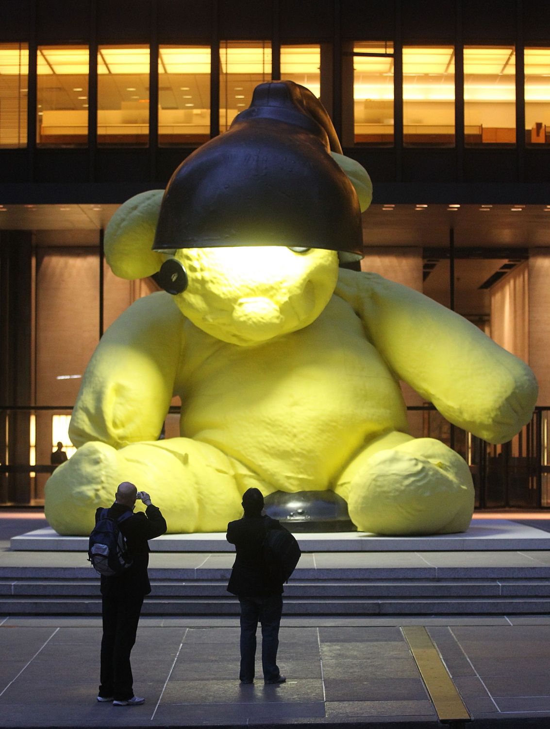 NEW YORK, NY - APRIL 08: People view the 23-foot "Unitled (LAMP/BEAR)" outdoor sculpture of a teddy bear by artist Urs Fischer April 8, 2011 in New York City. The 35,000 pound sculpture of a yellow teddy bear with a working lamp will be on display for five months in front of the Seagram Building in Manhattan. The sculpture is expected to sell for more than $10 million at ChristieÂs Post-War & Contemporary Evening Sale on May 11. (Photo by Mario Tama/Getty Images)