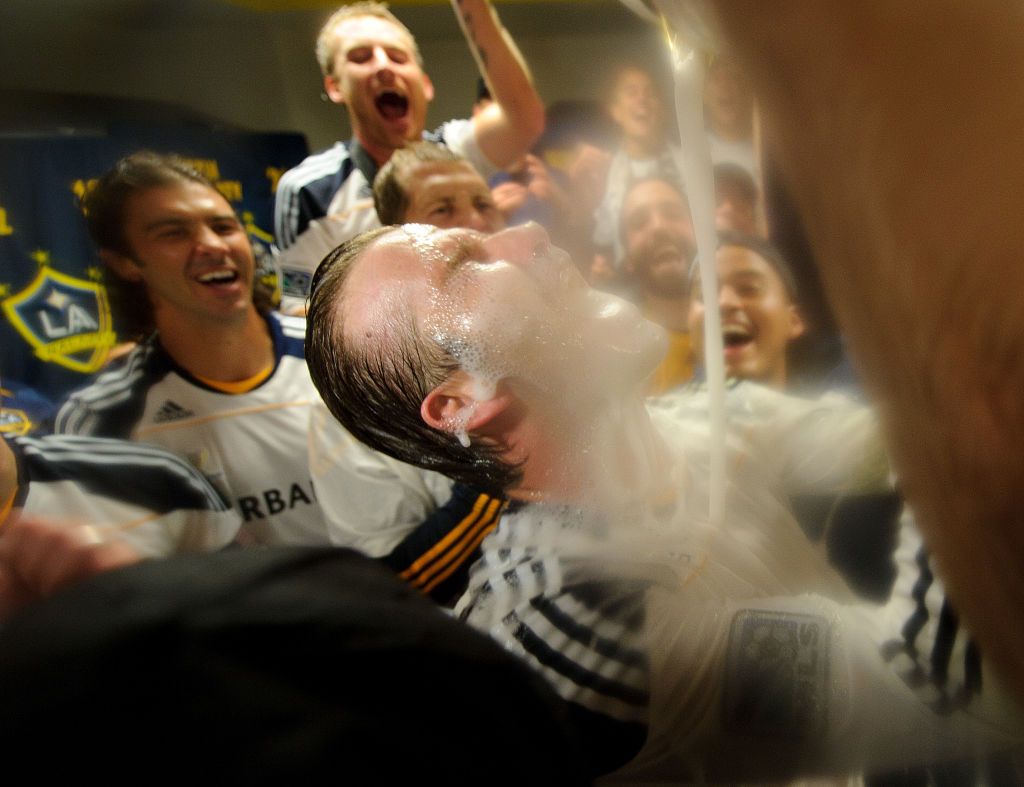 David Beckham of Los Angeles Galaxy celebrates in the dressing room with his team mates who pour champagne over his face after winning the MLS Cup defeating Houston Dynamo 1-0 in the final (Photo by Matthew Ashton/AMA/Corbis via Getty Images)