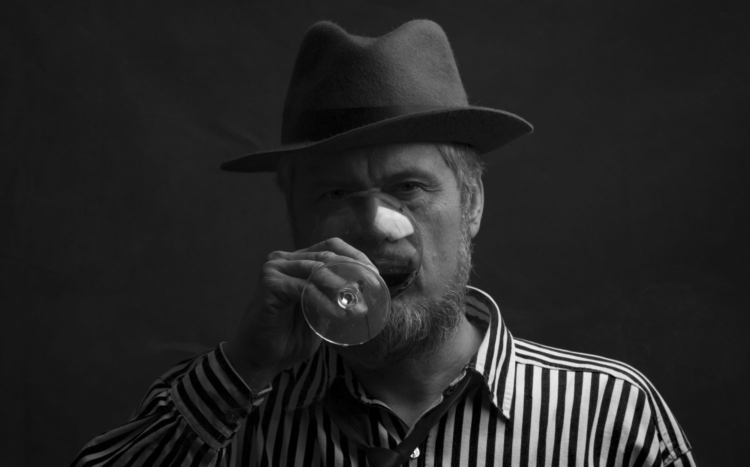 black and white portrait of a bearded man with a glass of wine