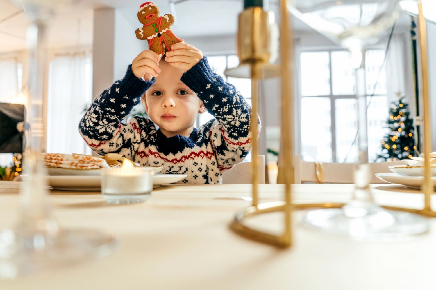 Little cute boy in a Christmas sweater eat gingerbread cookie in the New Year's kitchen.