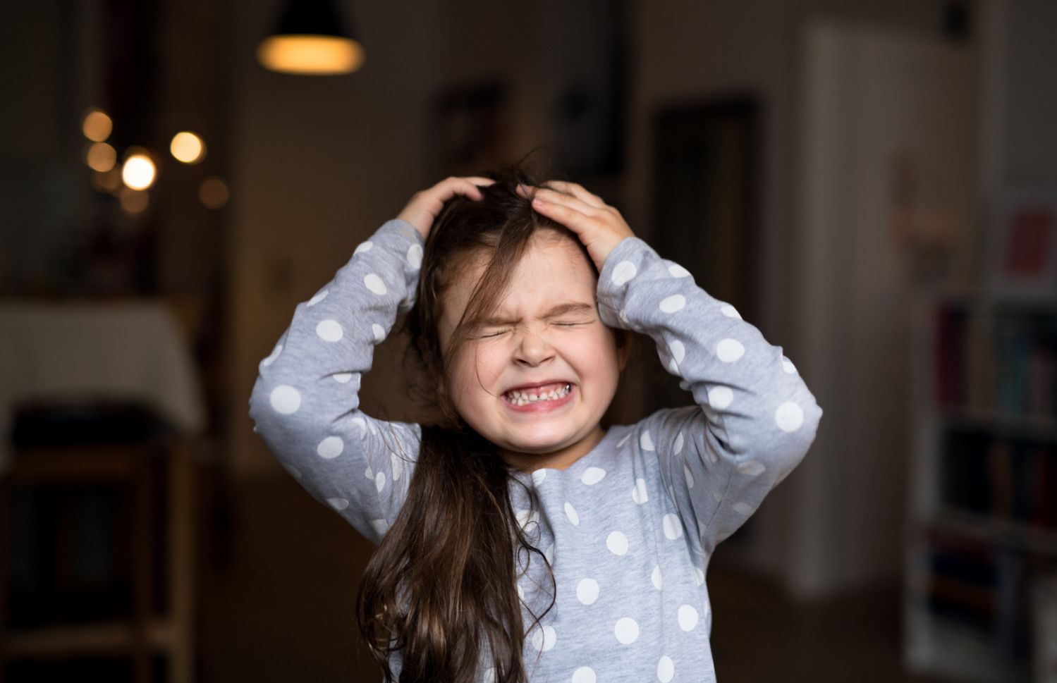 Unhappy small child in bedroom, eyes closed.