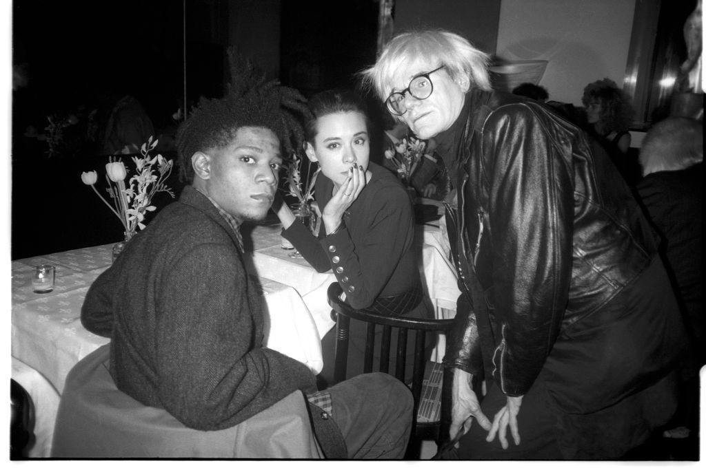 Jean-Michel Basquiat, Tina Chow, and Andy Warhol at Susan Blond's dinner party for Ozzy Osbourne at Mr. Chow's. April 21, 1986. (Photo by Patrick McMullan/Getty Images)