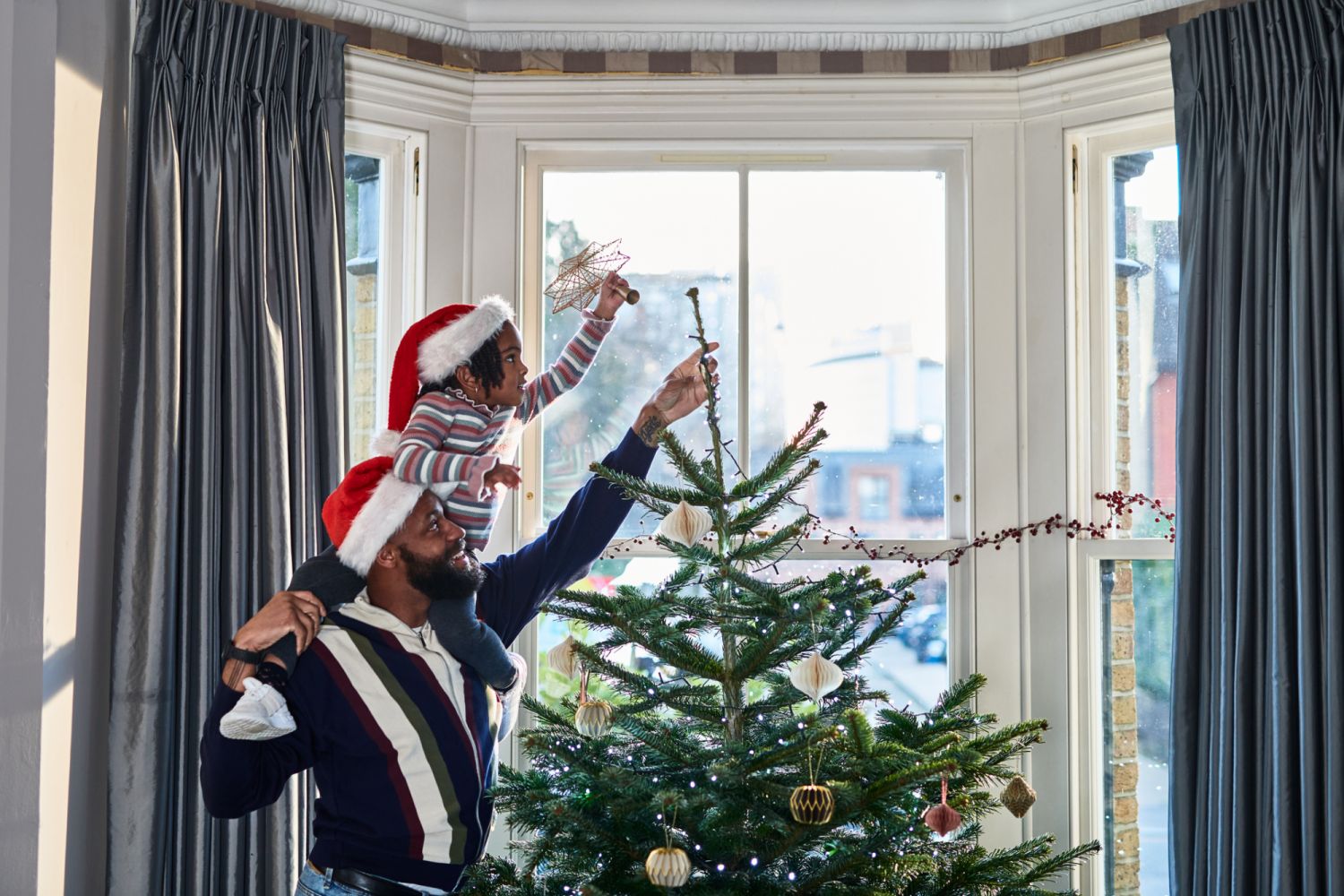 Father and daughter decorating Christmas tree in bay window at home, tradition, anticipation, childhood