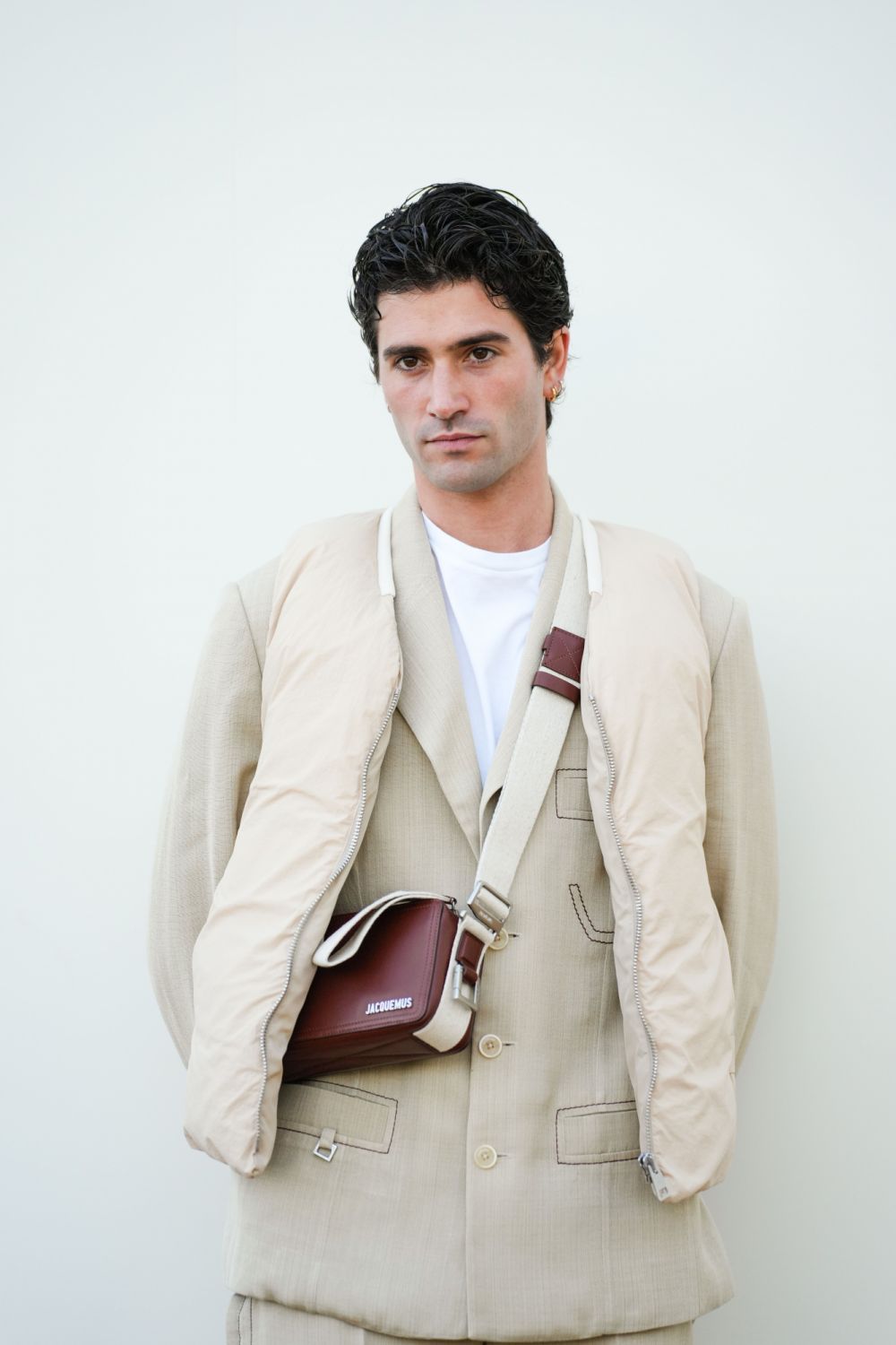 LE BOURGET, FRANCE - DECEMBER 12: Marc Forne wears a white t-shirt, a beige blazer jacket, matching suit pants, a beige sleeveless winter puffer jacket, a brown leather bag from Jacquemus, outside the "Le Raphia" Jacquemus show on December 12, 2022 in Le Bourget, France. (Photo by Edward Berthelot/Getty Images)