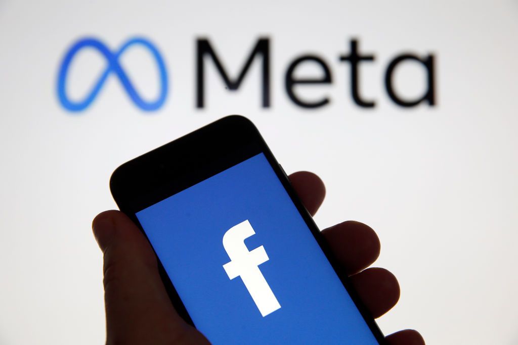 PARIS, FRANCE - OCTOBER 29: In this photo illustration, the Facebook logo is displayed on the screen of an iPhone in front of a Meta logo on October 29, 2021 in Paris, France. On October 28, during the Facebook Connect virtual conference, Mark Zuckerberg announced the name change of Facebook, believing that the term Facebook was too closely linked to that of the platform of the same name, launched in 2004. It is now official, the Facebook company changes its name and becomes Meta. (Photo illustration by Che