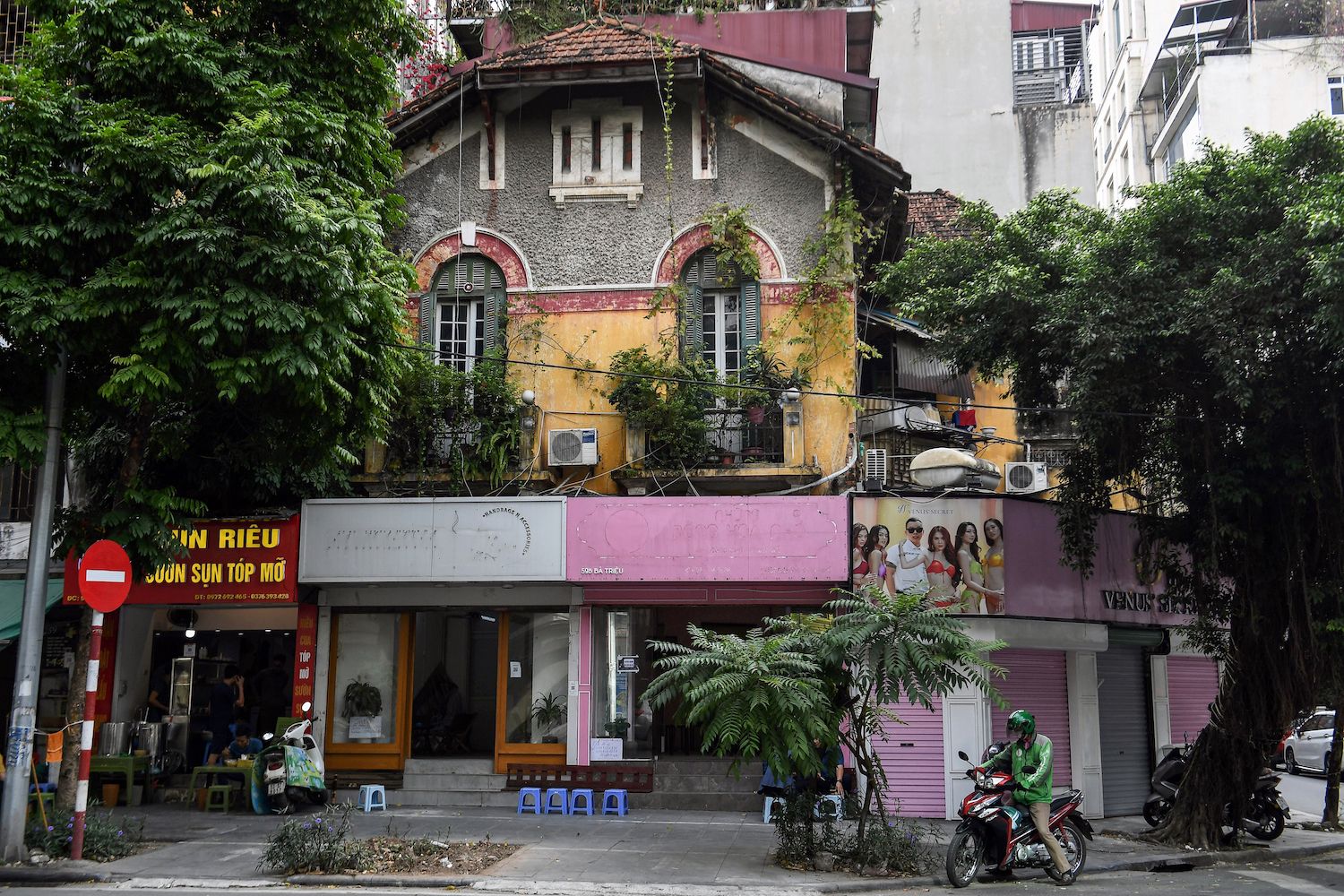 This photo taken on November 17, 2022 shows a motorbike taxi driver waiting for customers in front of an old villa in Hanoi. Most of the hundreds of French-style, century-old villas in central Hanoi have been degraded by age and humidity, and despite their protected status the future of these homes and their occupants hang in the balance, as residents struggle to afford their upkeep. (Photo by Nhac NGUYEN / AFP)